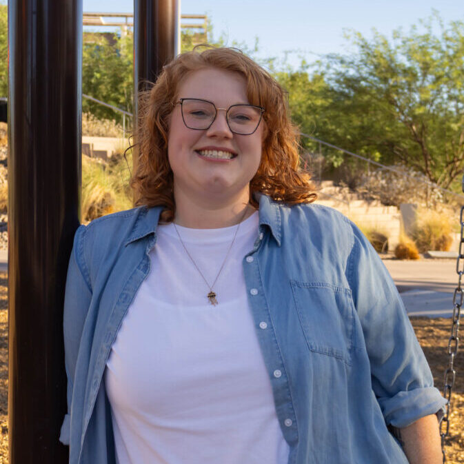 Dr Catherine Hallam leaning against the corner of a building, smiling.